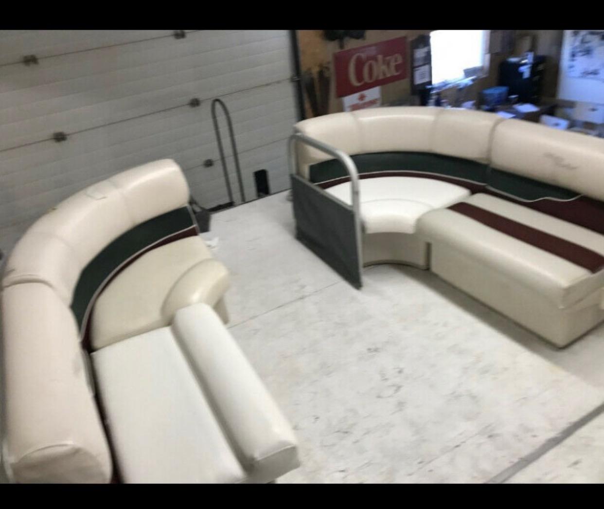 Pontoon boat bench seating reupholstered in cream vinyl with dark green and maroon accent stripes, shown in the workshop