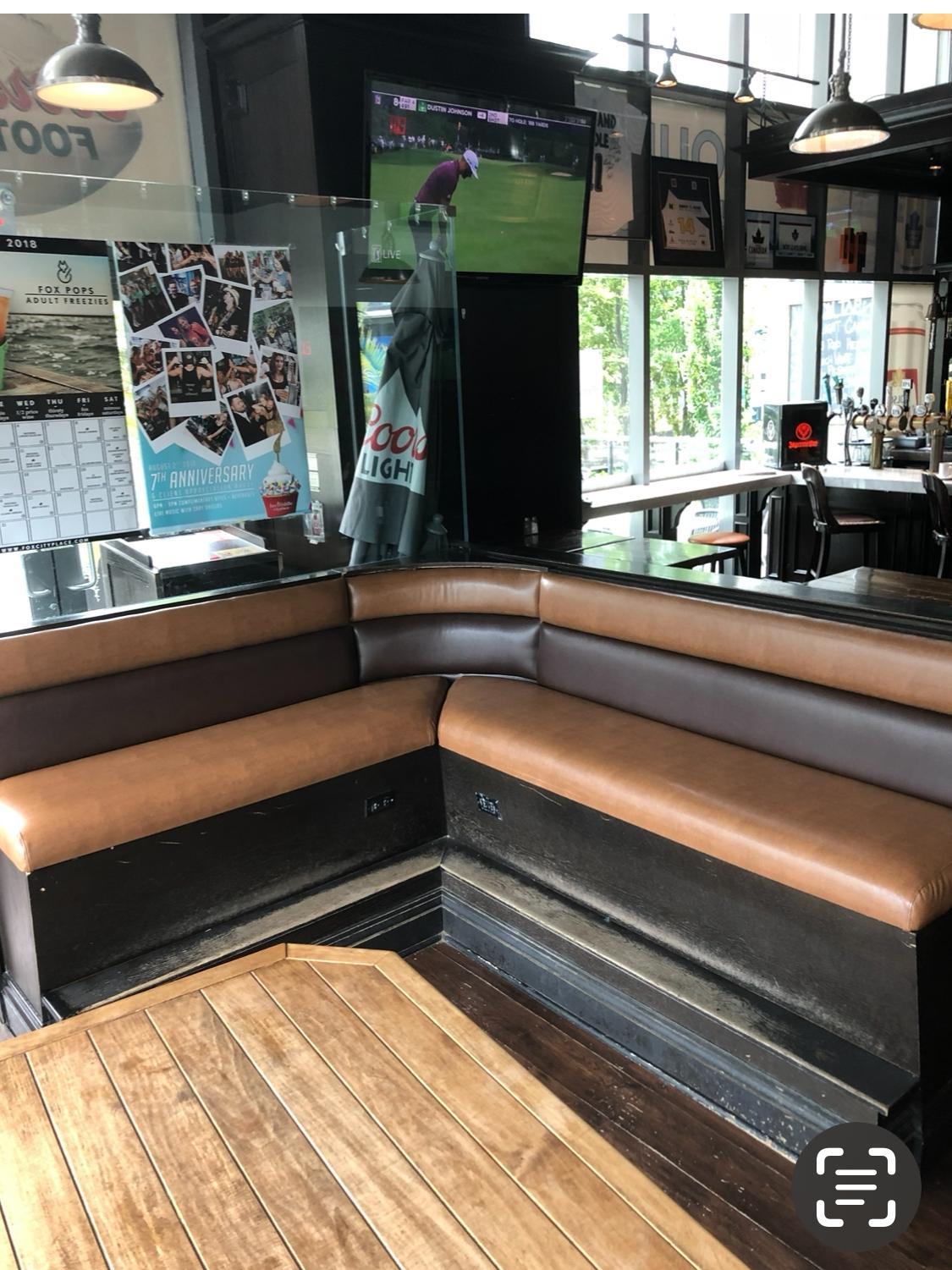 Corner booth seating in a sports bar reupholstered in tan and dark brown vinyl