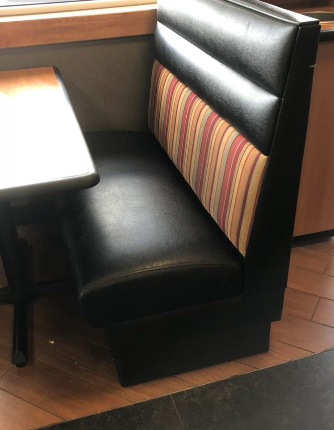 Restaurant booth seat reupholstered in black vinyl with a striped fabric backrest panel