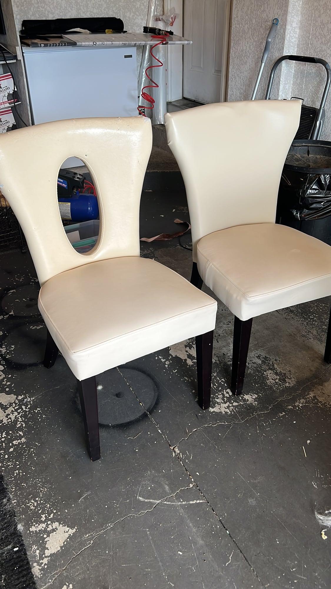 Pair of dining chairs with oval cutout backs, reupholstered in cream vinyl, photographed in the workshop