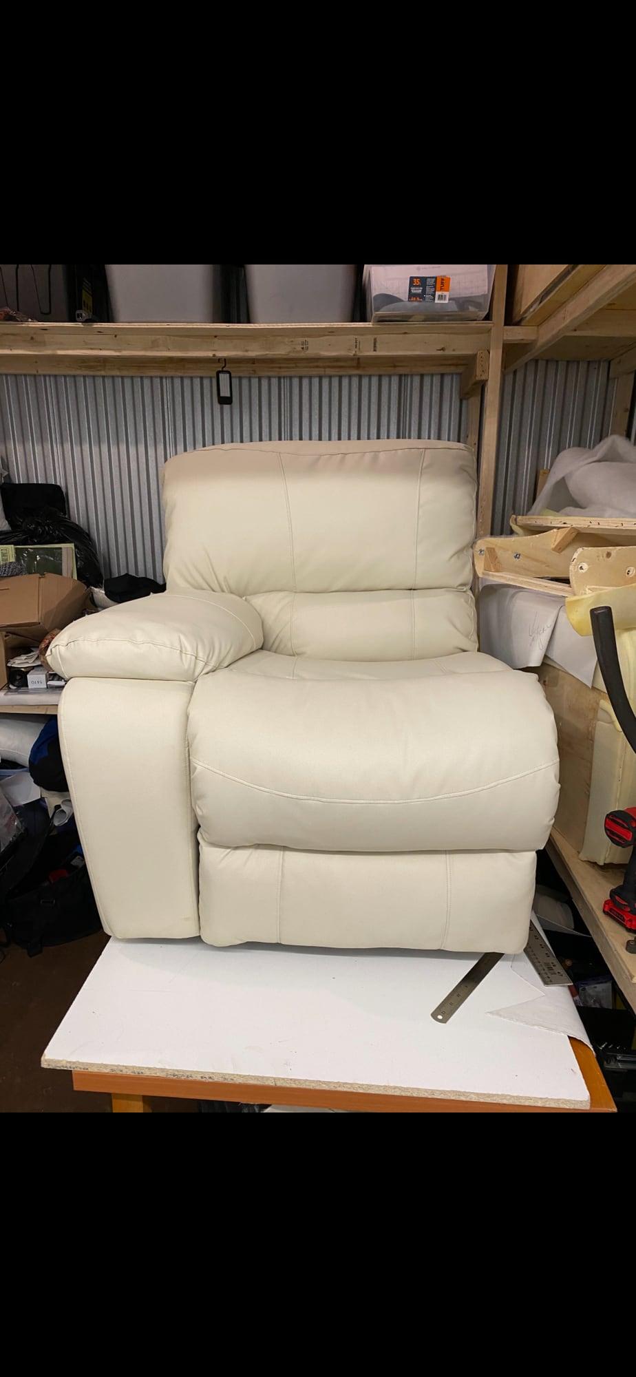 Reclining armchair reupholstered in cream leather-look vinyl, photographed in the workshop